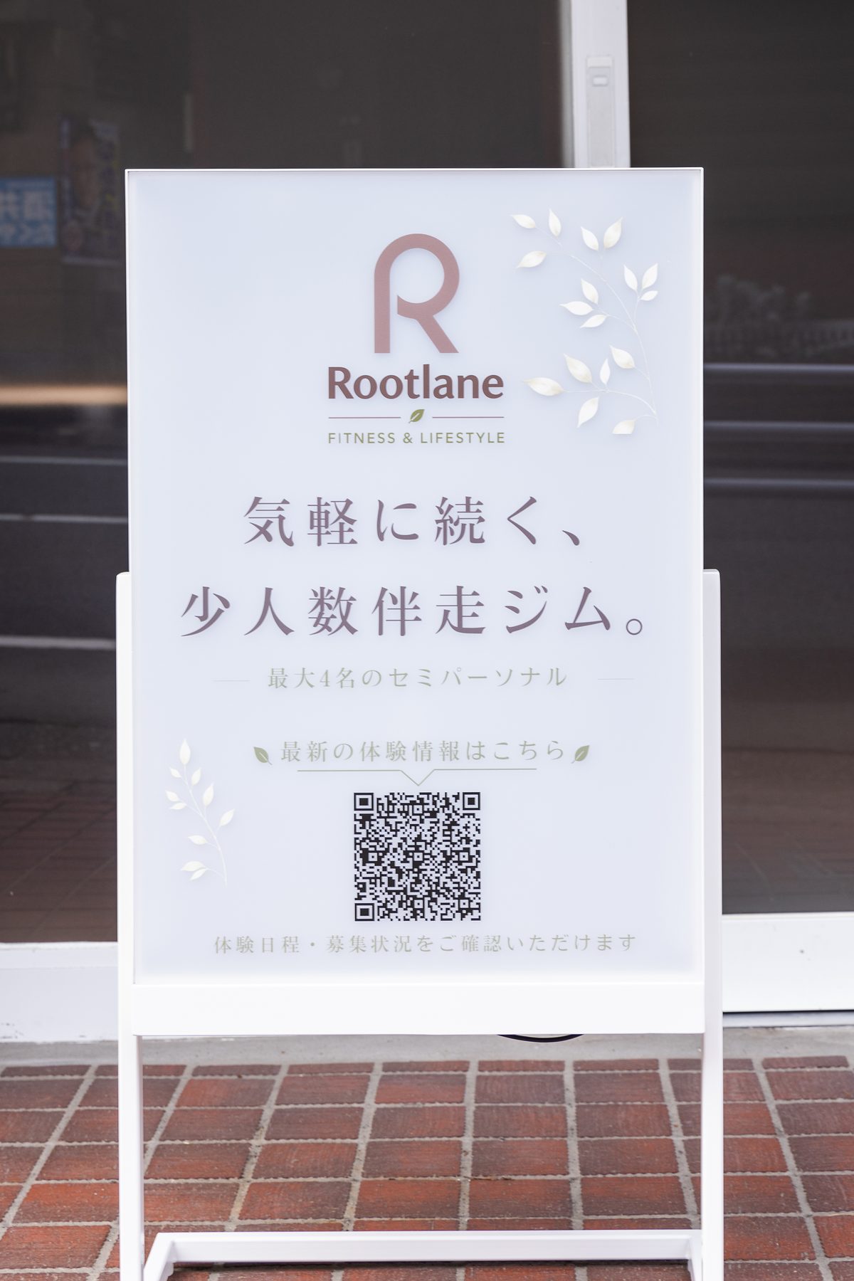 店頭に置かれた白い立て看板。ロゴと「気軽に続く、少人数伴走ジム。最大4名のセミパーソナル」の案内